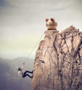 Young businessman scaling a rock to reach a large payoff