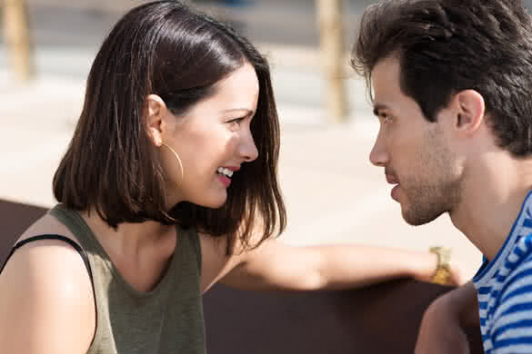 Profile view of an attractive young couple sitting staring intently into each other eyes